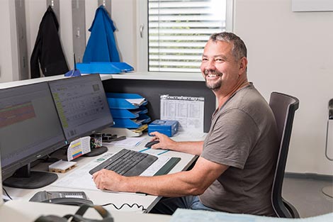 Mario Hochreiter bei der Arbeit - er sitzt vor dem PC und bedient gerade die Maus.